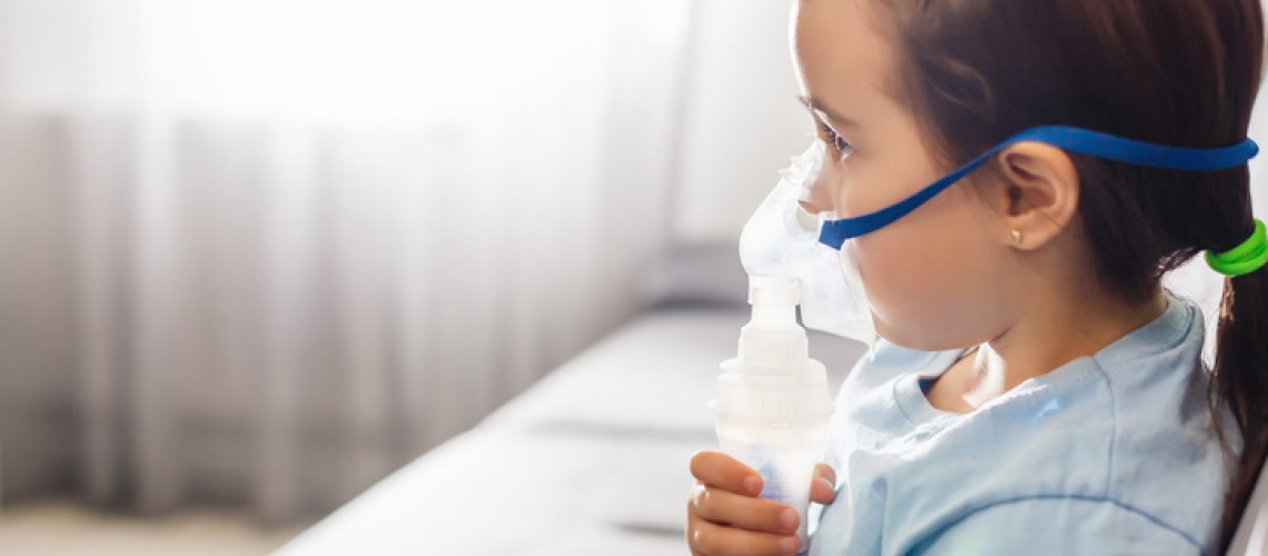 Little girl in a mask, treatments respiratory tract with a nebulizer at home