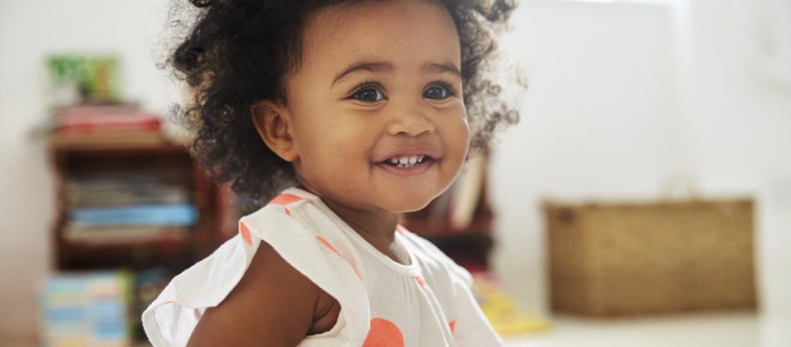 Happy Baby Girl Playing With Toys In Playroom